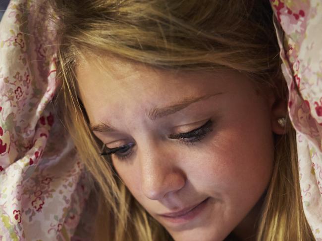 Unhappy Teenage Girl Sending Text Message Whilst Lying In Bed