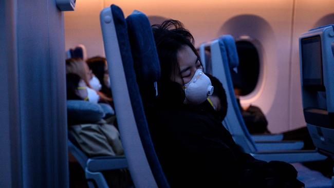 File picture: Passengers wearing protective face masks sleep on their flight to Shanghai on February 4. (Photo by NOEL CELIS / AFP)