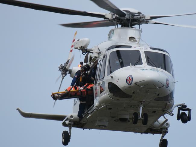 In you go, the man is loaded into the Toll helicopter. Pictures: Richard Noone