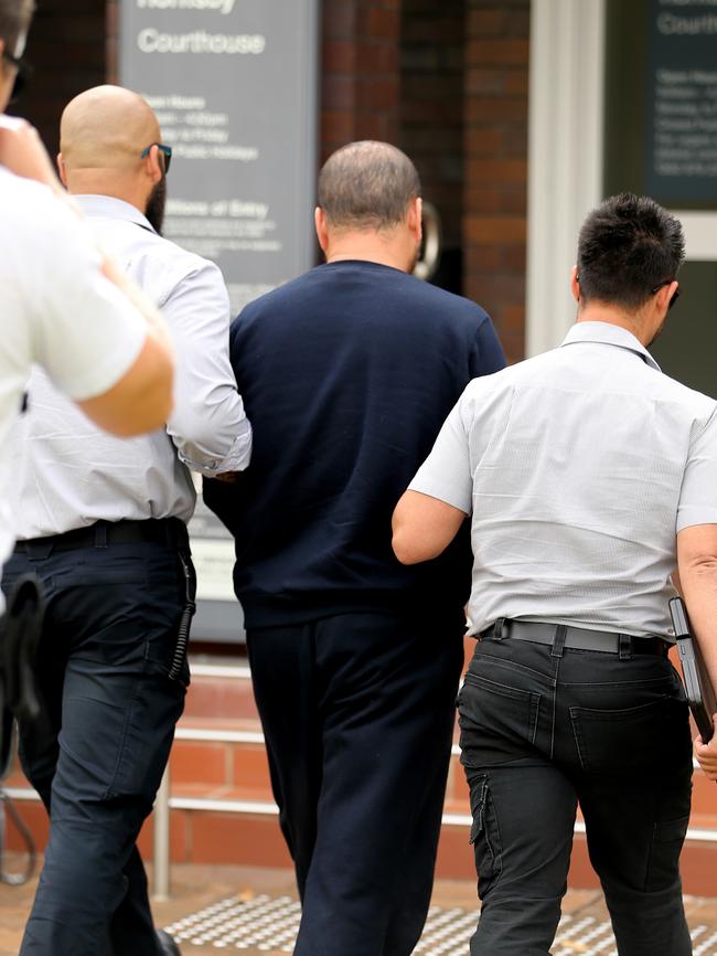 Ebrahim Qasimi is handcuffed and escorted into court. Picture: John Grainger