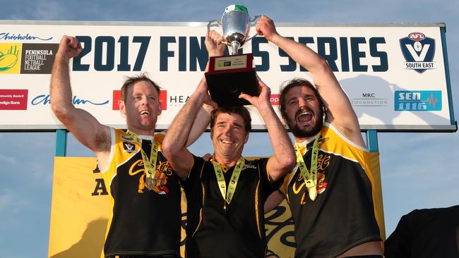 YCW coach Wayne Capp and co-captains Jie Coghlan and Kevin Lylak hold up the premiership cup in 2017. Picture: Mark Dadswell