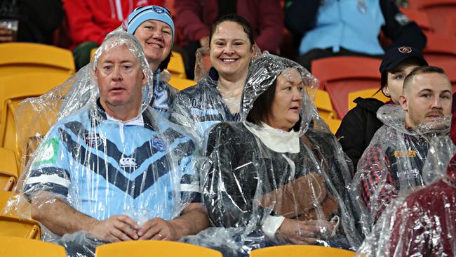 Fans take cover as rain falls at Suncorp Stadium. Picture: Annette Dew