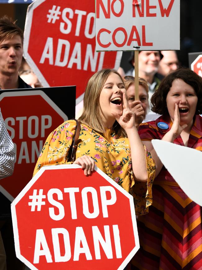 Anti-Adani protesters hold placards outside the offices of engineering and construction company GHD in Brisbane, Tuesday, July 30, 2019. (AAP Image/Dan Peled)