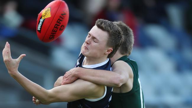 Ballarat’s Jed Hill tries to control the ball as he is tackled by Hampden’s Hamish Sinnott. Picture Yuri Kouzmin