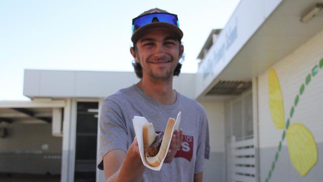 Josh Graveling holds up a democracy sausage at the Braitling Primary School snag stand, outside the school's voting centre in Alice Springs for the 2025 federal election, May 3, 2025. Picture: Gera Kazakov