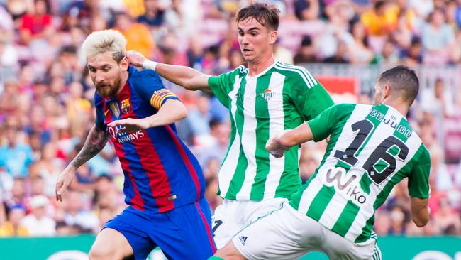 Lionel Messi of FC Barcelona dribbles Fabian Ruiz (2nd R) and Alvaro Cejudo (R).
