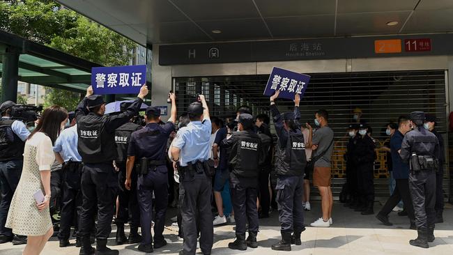 Police officers look at people gathering at the Evergrande headquarters in Shenzhen, southeastern China, as the property giant said it was facing ‘unprecedented difficulties’. Picture: AFP