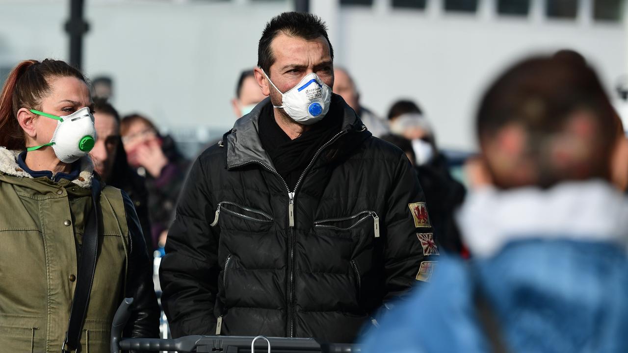 Residents wearing a respiratory mask wait to be given access to shop in a supermarket in small groups of forty people in the small Italian town of Casalpusterlengo. (Photo by Miguel MEDINA / AFP)