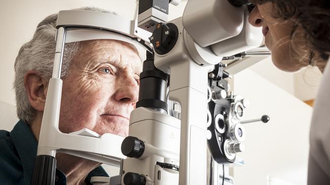 Optometrist giving eye exam to senior patient