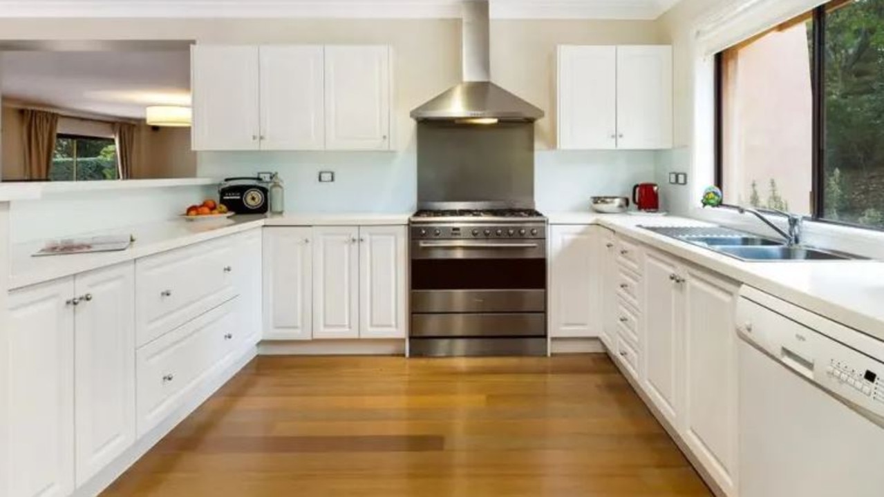 The modern kitchen has gas cooking and stone benchtops.