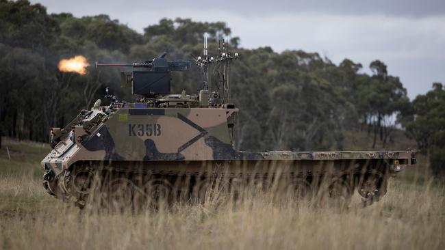 An Australian Army M113AS4 armoured logistics vehicle, fitted with optionally crewed combat vehicle technology and a remote weapon station, fires from a support-by-fire position during a human-machine team exercise at Puckapunyal Military Area.