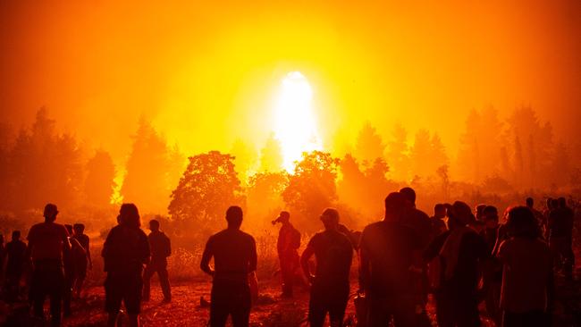 Local youths and volunteers gather in an open field and wait to support firefighters during a wildfire next to the village of Kamatriades in Greece. Picture: ANGELOS TZORTZINIS / AFP