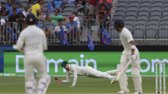 India's Virat Kohli, left, and Ajinkya Rahane look on as Australia's Peter Handscomb dives to stop the ball during play. Picture: AAP