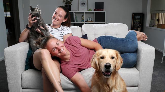 Megan Schutt, has undergone IVF treatment in a quest to start a family with her wife Jess. They are pictured with Eddie the golden retriever and Whitney the cat. Picture: Sarah Reed.