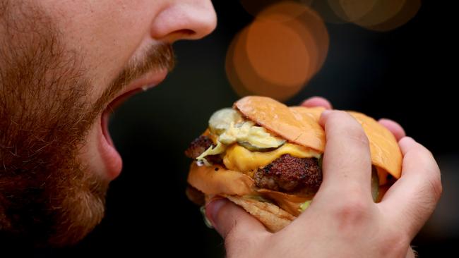 A Penrith Press journalist tucks in to one of Burger Head’s Cease and Desist burgers. Picture: AAP Image/Angelo Velardo.