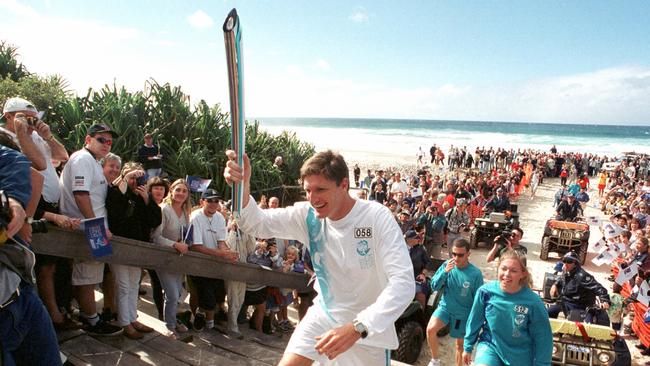 Trevor Hendy carrying torch at Surfers Paradise beach during Olympic torch relay