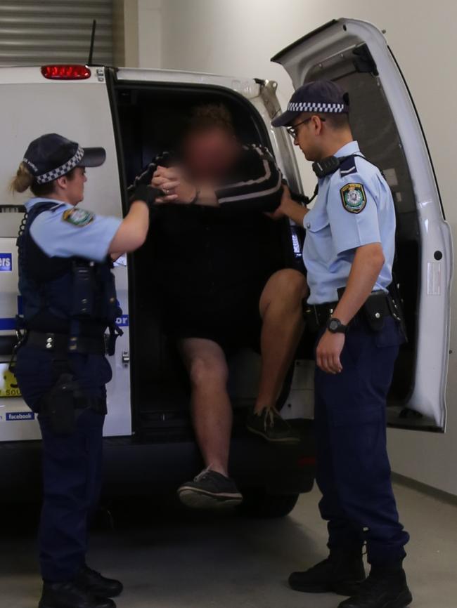 Officers from the Child Abuse Squad pull the accused out of a police van today. Picture: NSW Police Force