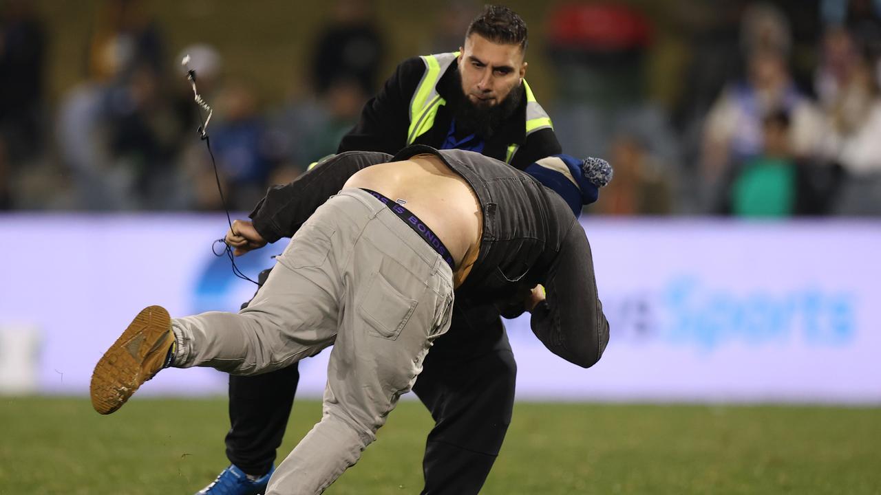 A pitch invader is apprehended during the Test match between Papua New Guinea and Fiji. (Photo by Mark Kolbe/Getty Images)