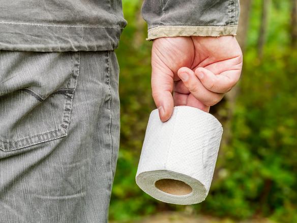 Man holding toilet paper in woods
