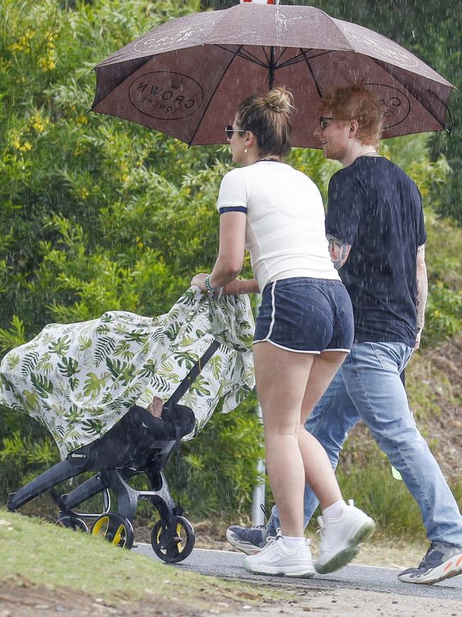 Ed and Cherry made a dash back to their accomodation in the rain with the help of their security guard and multiple umbrellas. Picture: MEDIA-MODE.COM