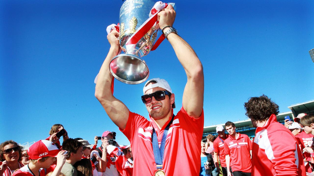 Champion midfielder Josh Kennedy holds the 2012 premiership cup aloft after arriving back in Sydney. He will retire at season’s end.