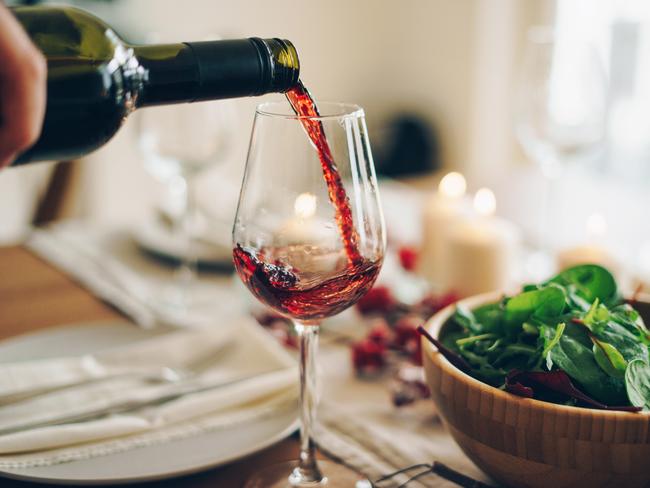 Red wine being poured into the glass at the table