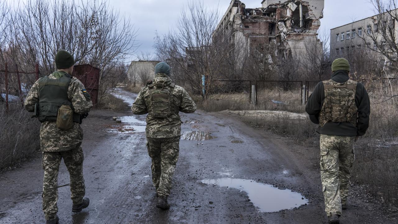 Ukrainian soldiers walk past destroyed buildings on December 8, 2021 in Marinka, Ukraine. Picture: Getty Images