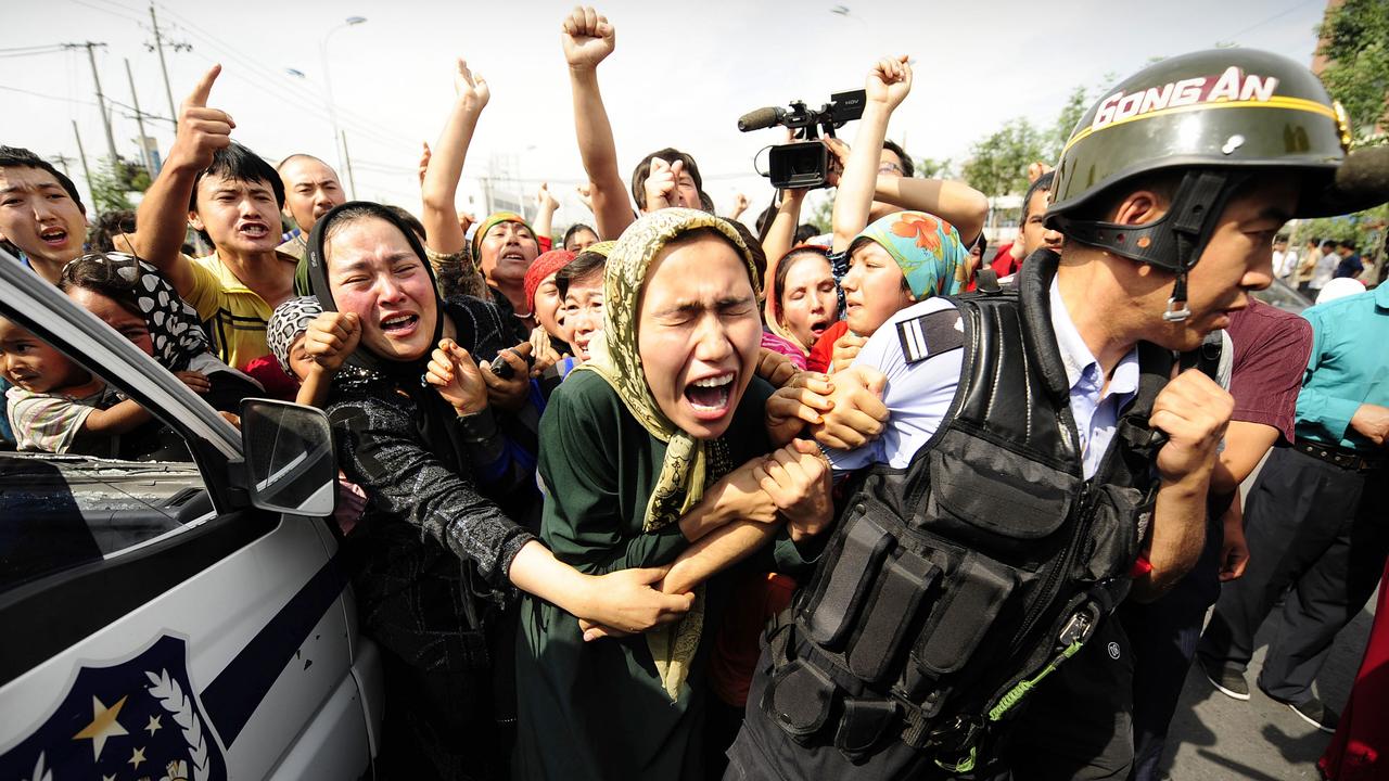 Ethnic Uighur women grab a riot policeman as they protest in Urumqi in China's far west Xinjiang province in 2009. Picture: Peter Parks/AFP