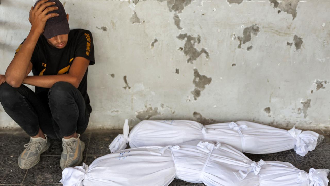 A boy sits by the shrouded bodies of children killed by an Israeli bombardment. Picture: Omar Al-Qattaa/AFP