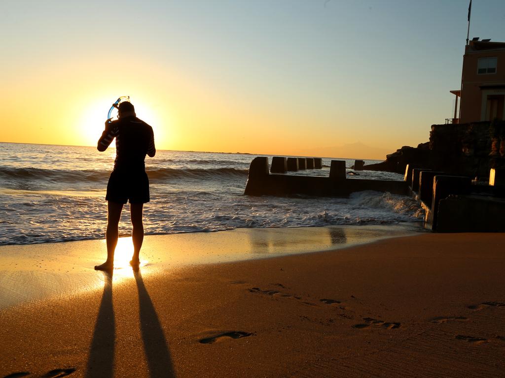 A snorkler is eclipsed by a clear sunrise at Coogee Beach. Picture: John Grainger