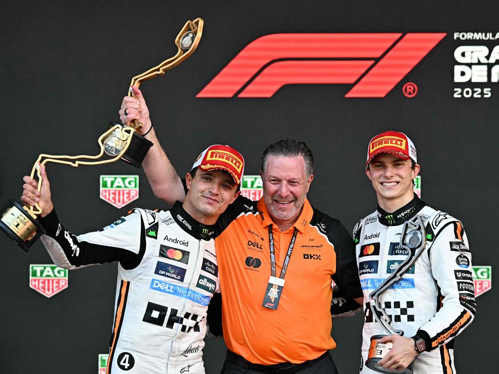 Lando Norris lifts his trophy in the air to celebrate his win at Monaco, alongside McLaren's CEO Zak Brown and third-placed teammate Oscar Piastri. Picture: AFP