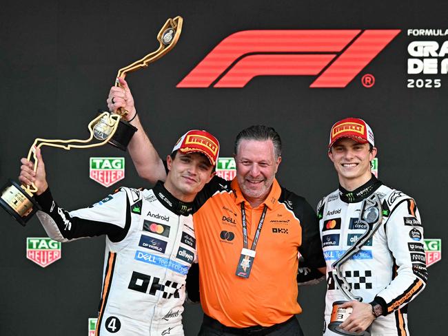 Lando Norris lifts his trophy in the air to celebrate his win at Monaco, alongside McLaren's CEO Zak Brown and third-placed teammate Oscar Piastri. Picture: AFP