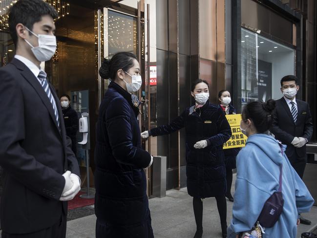 Staff members wearing face masks are seen at an entrance of a Wuhan business plaza in Hubei Province, China. Picture: Getty