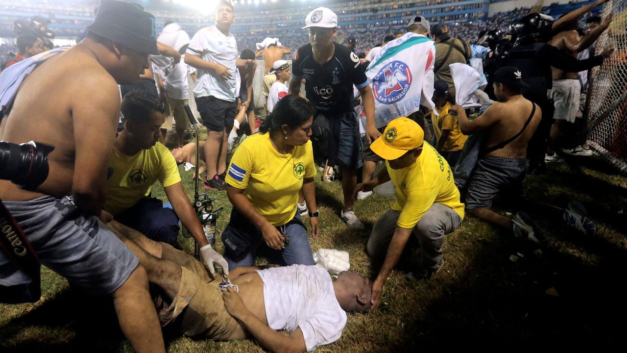 Rescuers attend an injured man lying on the pitch following the stampede in El Salvador. Picture: Milton Flores/AFP