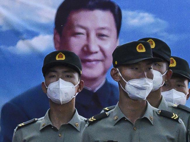 BEIJING, CHINA - MAY 20: Soldiers of the People's Liberation Army's Honour Guard Battalion wear protective masks as they stand at attention in front of photo of China's president Xi Jinping at their barracks outside the Forbidden City, near Tiananmen Square, on May 20, 2020 in Beijing, China. China's government will open its annual weeklong meetings known as the 'two sessions' at the Great Hall of the People on May 21st. They were delayed in March due to the COVID-19 pandemic. After decades of growth, officials recently said China's economy had shrunk in the latest quarter due to the impact of the coronavirus epidemic. The slump in the worlds second largest economy is regarded as a sign of difficult times ahead for the global economy. While industrial sectors in China are showing signs of reviving production, a majority of private companies are operating at only 50% capacity, according to analysts. With the pandemic hitting hard across the world, officially the number of coronavirus cases in China is dwindling, ever since the government imposed sweeping measures to keep the disease from spreading. Officials believe the worst appears to be over in China, though there are concerns of another wave of infections as the government attempts to reboot the worlds second largest economy. Since January, China has recorded more than 82,000 cases of COVID-19 and at least 4000 deaths, mostly in and around the city of Wuhan, in central Hubei province, where the outbreak first started. (Photo by Kevin Frayer/Getty Images)