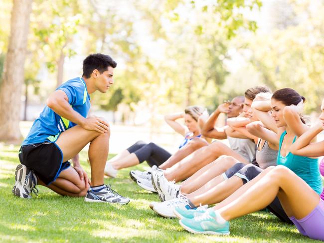 RendezView. Young male instructor motivating people in doing sit-ups at park. (Pic: iStock)