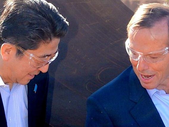 Australian Prime Minister Tony Abbott (R) and Japanese Prime Minister Shinzo Abe pose for a photograph next to a haulage truck tyre during a tour of Rio Tinto's West Angelas iron ore mine in Pilbara, Western Australia on July 9, 2014. Abe is visiting New Zealand, Australia and Papua New Guinea to hold talks with officials on biliateral and international issues. AFP PHOTO/POOL/ALAN PORRITT