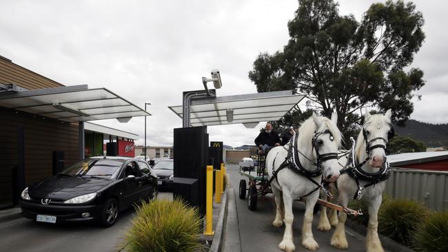 Lex Clark orders ice creams for his Shire horses, Max (left) and Sparky at the McDonald's drive through in New Norfolk.