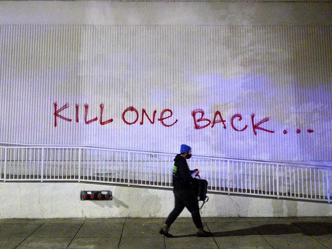 A demonstrator passes graffiti in Oakland, California, where an officer was shot dead. Picture: AP