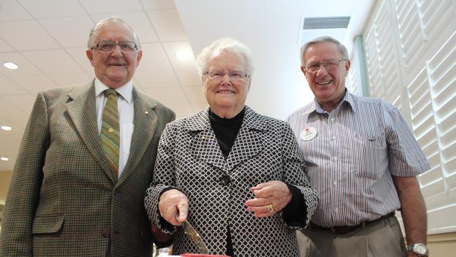 SLICE OF LIFE: John Adams, Shirley Adams and Bob McFarlane cut the cake at Red Cross centenary celebrations in Grafton on May 8. Photo Clair Morton / Daily Examiner