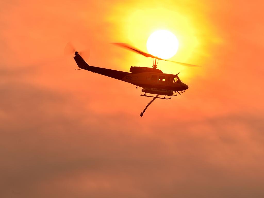 A helicopter prepares to drop water on a large bushfire in NSW. Photo by Peter PARKS / AFP)