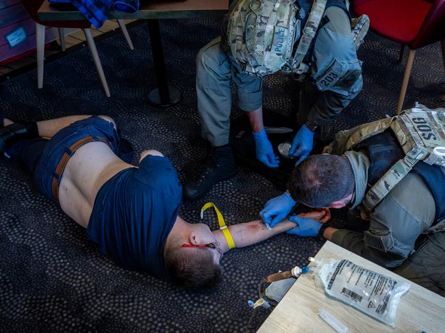 An officer inserts a drip into a patients’ arms to stabilise the victim until paramedics arrived as part of the staged training exercise. Picture: Jake Nowakowski