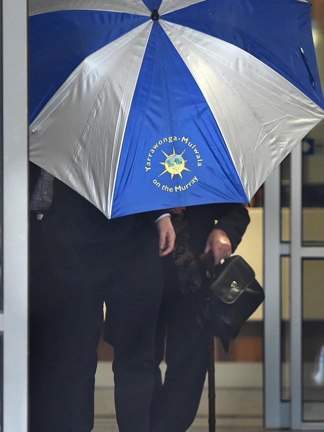 The trio tried to hide from media behind an umbrella. Picture: Nicole Garmston