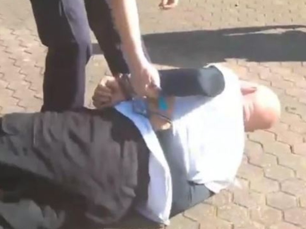 The man appears to have a seizure in Brisbane Botanical Gardens after being arrested.