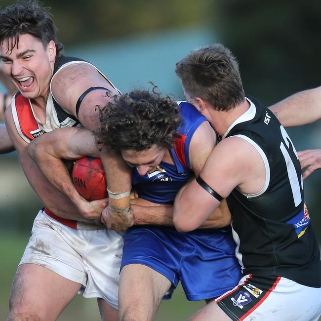 Terang-Mortlake’s Rhys Buck tries to fight off two Koroit opponents.