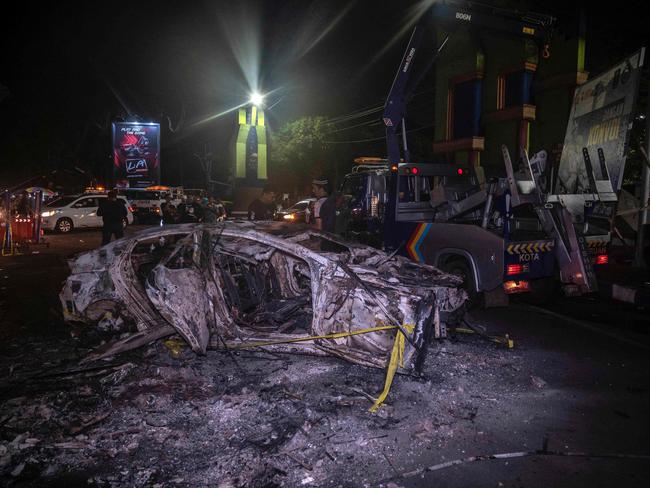 People stand next to a torched vehicle outside the Kanjuruhan stadium in Malang, East Java. Picture: AFP