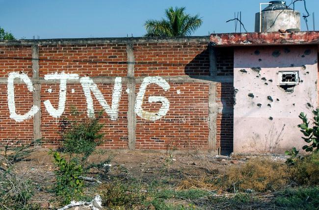 The initials of the Jalisco New Generation Cartel (CJNG) are seen on a bullet-riddled wall in Mexico's Michoacan state