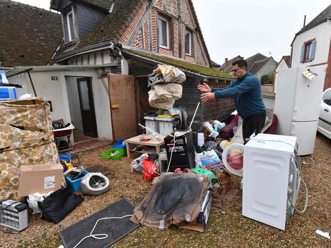 A resident takes the ruined contents of his home to the front lawn. Picture: AFP.