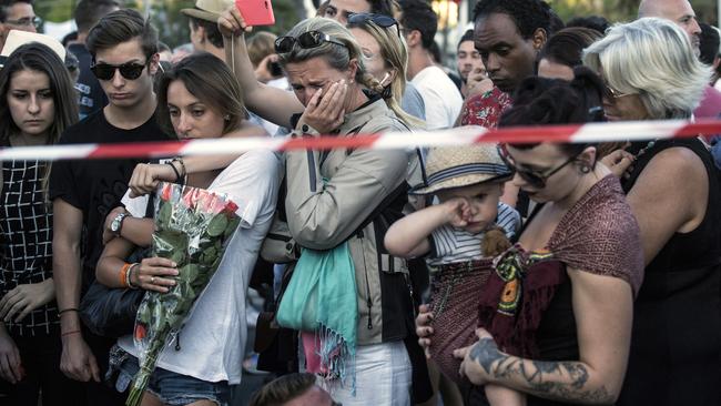 People react as they gather at a makeshift memorial to honor the victims of an attack, near the area where a truck mowed through revelers in Nice, southern France, Friday, July 15, 2016. A large truck mowed through revelers gathered for Bastille Day fireworks in Nice, killing more than 80 people and sending people fleeing into the sea as it bore down for more than a mile along the Riviera city's famed waterfront promenade. (AP Photo/Laurent Cipriani)