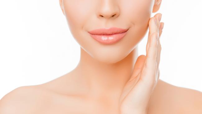 REAL DOLLS FEATURE stock image. Picture: iStock Close up of woman with perfect skin applying cream on face